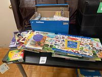 Overview of kids books, sticker collection, crayons, and craft box arranged on a table.