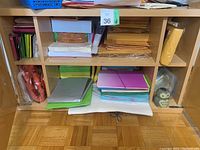 Full view of the cabinet holding the lot showing paper stacks, envelopes, file sleeves, and the owl sharpener