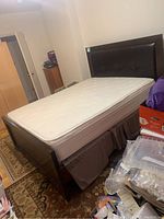 Full side view of the queen size bed frame with upholstered headboard and mattress on top, dark wood finish visible
