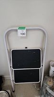 Full front view of the metal step ladder showing two black steps and white metal frame.