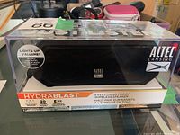 Front view of Altec Lansing Hydrablast wireless speaker in clear plastic packaging showing branding, product name, and waterproof features.