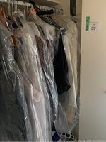 Hanger rack with multiple women's medium clothing items protected by plastic garment covers.