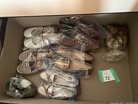 Overhead view of six pairs of women's shoes in a box, mostly beige, white, and brown colors, wrapped in plastic bags.