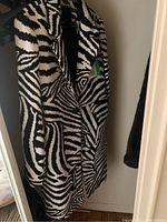 Front view of the women's zebra print jacket hanging on a black hanger, showing its zebra stripe pattern and lapel.