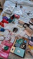 Overview of lot on bed showing travel pouches, jewelry boxes, loose jewelry
