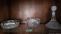 Crystal bowls and ships decanter displayed on a shelf showing entire set