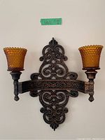 Front view of one vintage double arm wall sconce with curved scroll ornate design and amber hobnail glass votive candle holder