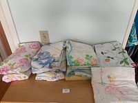 View of all folded sheets with floral patterns and the ballerina print sheet in front.