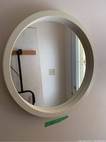 Photo of a round wall mirror with a white frame mounted on a wall.