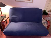 Photo of small blue reclining sofa with wooden armrests showing upholstery and seat cushion surface