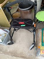 Front view of black walker with padded seat, front wheels, and ergonomic handles