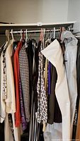Photo showing variety of hanging women’s clothes including blazers, pants, and dresses in assorted patterns and colors