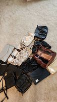 Overview of lot showing various vintage purses and bags in leather, suede, and fabric on carpet floor.