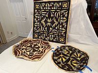 Wall hanging and two circular leather pieces displayed upright and flat