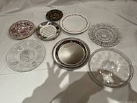 Top view of the eight plates showing mix of decorated ceramic and clear patterned glass plates, including musical motif plates.