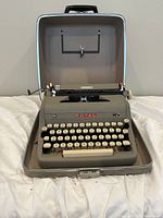 Gray Royal Quiet De Luxe manual typewriter in its open carrying case showing keyboard and front panel.