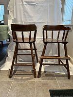 Front view of two wooden child chairs showing seat, backrest, spindle supports, and legs with stretchers