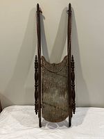 Full front view of Victorian wooden sled showing the wooden body, side rails, red and white rope, and metal runners securing the crack.