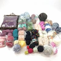 Collection of yarn skeins and balls in various colors and textures laid out on white background