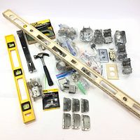 Lot overview showing spirit levels, hammer, electrical boxes, electrical components, hinges, and other hardware in used but good condition.