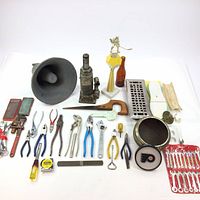 Photo showing full array of handyman tools including pliers, wrenches, a bottle jack, trophies, loudspeaker horn, and small hand tools.