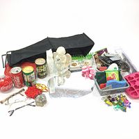 Wide shot showing various items including collectable drink cans, toys, decorations, storage containers, and eyeglasses spread over a white surface.