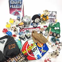 Full view of all items showing memorabilia, figurines, golf putting game, stuffed bear, mini hockey net, Flyers jacket, and other assorted collectibles primarily hockey-themed.