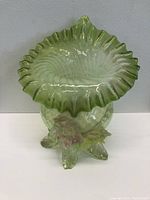 Front view of antique green glass tulip vase showing ruffled flared top and spiral body texture with floral and leaf base decoration.