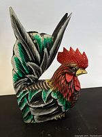 Side view of hand painted wooden rooster showing detailed feather work and red comb.
