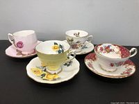 Four different tea cup and saucer sets arranged in a row showing floral designs and color variations.