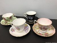 Lot displaying four porcelain tea cups and matching saucers in floral designs and gold trim.