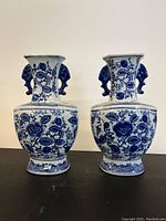 Front view of the pair of blue and white Asian vases showing floral patterns and elephant head handles.