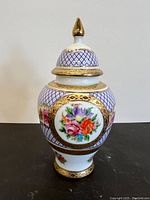 Front view of porcelain Limoges jar showing floral patterns and gold accents on lid and body.