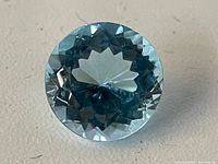 Top view of round blue topaz stone showing facets and color