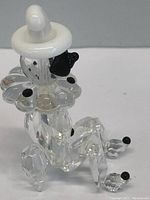 Side angle of the transparent crystal clown showing its detailed faceting, white hat, and black bow tie.