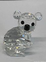 Clear Swarovski crystal koala figurine sitting, faceted to reflect light, black eyes and nose visible.