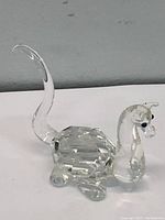 Full view of the Swarovski mythical beast figurine showing its faceted oval body, curved upright tail, and clear crystal head with black eyes.