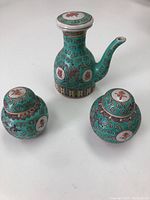 Full set of vintage Asian porcelain items: one tea pot and two ginger jars, all decorated in turquoise with red Asian characters and colorful patterns.