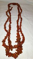 Two Baltic amber necklaces laid flat on white cloth background showing bead size variation.