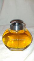 Front view of Burberry perfume bottle showing yellow-orange liquid, silver cap and BURBERRY marking in silver on front.