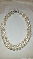 Photo showing the full double strand pearl necklace laid flat, displaying the magnetic clasp and two different strand sizes.