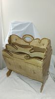 Front view of the gold-painted wooden magazine rack showing four compartments and scalloped edges.