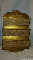 Front view of wooden letter holder with gold decorative accents and three compartments.