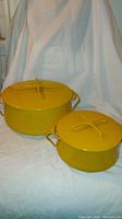 Two yellow enamel Dansk pots with lids, showing overall look and design