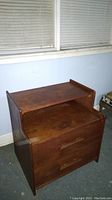 Front view of the teak wood side dresser showing two drawers and top shelf in dark wood finish.
