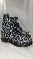 Side view of black leather Doc Martens boots with floral chintz pattern and laces tied.