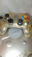 Close-up of clear transparent Xbox controller over console top showing Xbox logo