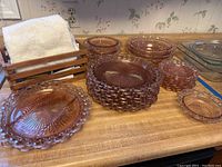 Wide angle view of the carnival glass dinnerware showing plates, bowls, relish dishes, and wooden crate with towels