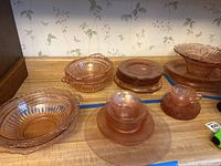 Overview of various sized carnival glass dishes including plates and bowls on countertop.