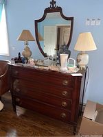 Full front view of wooden dresser with mirror and various decorative items on top.